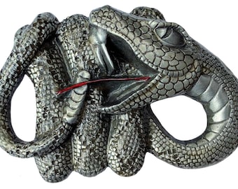 Peut inclure: Une boucle de ceinture en métal argenté représentant une sculpture détaillée d'un serpent se mordant la queue. Le serpent est enroulé et présente une apparence texturée et écailleuse.