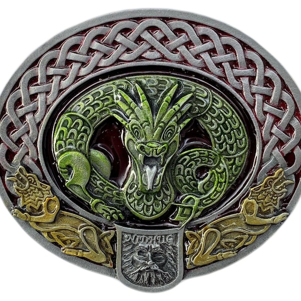 Könnte beinhalten: Ovale Gürtelschnalle mit einem grünen Drachendesign in der Mitte, umgeben von einem silbernen keltischen Knotenmuster und einem roten Hintergrund. Zwei goldfarbene Tierfiguren befinden sich unten. Ein kleines Schild mit einem Gesicht befindet sich unten.