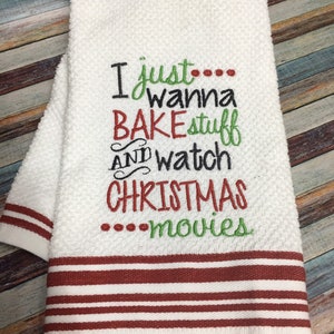 May include: White kitchen towel with red stripes. The towel has an embroidered design that says "I just... wanna bake stuff and watch Christmas... movies".