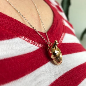 Woman wearing an anatomical heart model pendant in gold