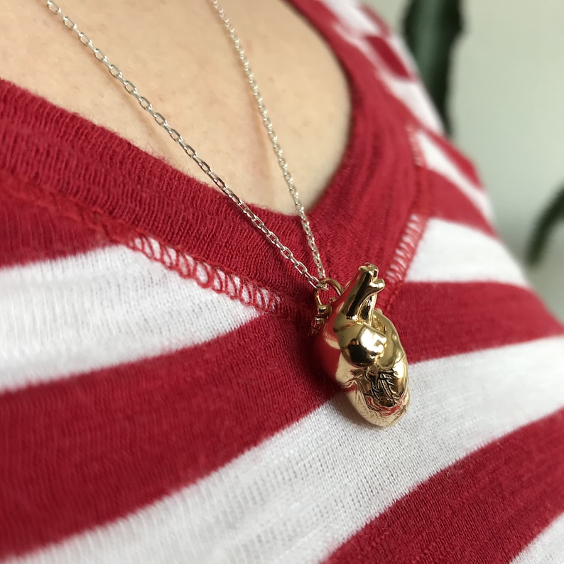 Woman wearing an anatomical heart model pendant in gold