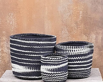 Puede incluir: Tres cestas tejidas en blanco y negro a rayas, de diferentes tamaños. Las cestas están hechas de materiales naturales y tienen un aspecto rústico y artesanal.