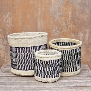 May include: Three woven baskets with black and white geometric patterns. The baskets are made of natural materials and are a great way to add a touch of style to any room.