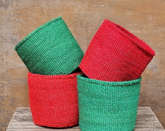 May include: Four woven baskets in a stacked arrangement. Two are a vibrant red, and two are a bright green. The baskets have a cylindrical shape and are made of a textured material, likely natural fibers. The background is a textured, neutral color.
