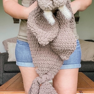 Puede incluir: Un gran peluche de morsa hecho a mano, tejido a ganchillo en marrón, con colmillos blancos. El peluche tiene un aspecto texturizado y grueso y lo sostiene una persona. La morsa tiene un hocico marrón claro y ojos oscuros. La fecha "Sep 16, 2022" es visible.