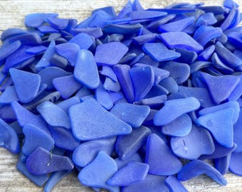 May include: A large pile of cobalt blue sea glass pieces. The glass is smooth and has been tumbled by the ocean.