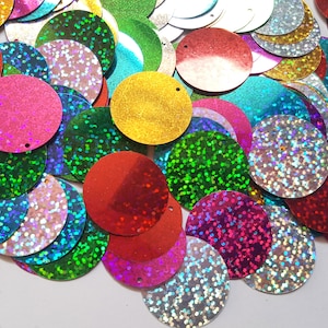 May include: Assortment of iridescent round sequins in various colors, including red, green, blue, gold, and silver. The sequins have a holographic finish and are perfect for crafting and decorating.