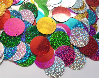 May include: Assortment of iridescent round sequins in various colors, including red, green, blue, gold, and silver. The sequins have a holographic finish and are perfect for crafting and decorating.