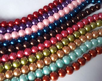 May include: A strand of colorful pearl beads in various shades of red, pink, blue, brown, green, and orange. The beads are arranged in rows, creating a visually appealing pattern.