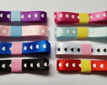 May include: Eight spools of satin ribbon with white heart patterns. The ribbons are in the colors purple, pink, light blue, blue, white, black, red, and dark red.