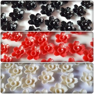 Peut inclure: Assortiment de fleurs en plastique noir, rouge et blanc. Les fleurs ont cinq pétales et un trou central.