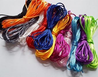May include: Assortment of colorful cords in various shades of blue, green, purple, pink, orange, red, white, and black. The cords are made of a smooth, silky material and are perfect for crafting.