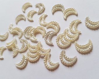 May include: A collection of white pearl crescent moon embellishments. The moons are made of plastic and have a pearl-like finish. They are perfect for adding a touch of elegance to crafts, jewelry, and other projects.