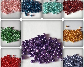 May include: Assortment of 10 colors of pearl beads. The beads are small and round, and they are arranged in a pile. The colors are pink, teal, blue, red, green, purple, gold, and silver.