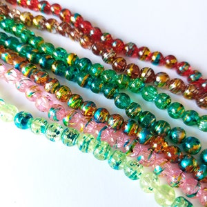 May include: Assortment of colorful glass beads with metallic accents. The beads are round and have a textured surface. The colors include red, green, pink, and clear.