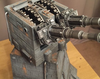 May include: A detailed model of a Star Wars Imperial Turbolaser, painted in a weathered gray and rust color scheme. The model features a rotating turret with two barrels and a complex gear system. The model is mounted on a base with a textured surface.
