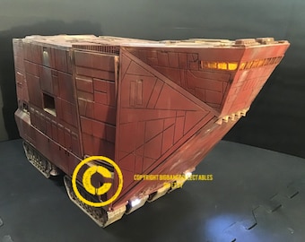 May include: A large, red, detailed model of a fictional spacecraft with a ramp in the back. The model has a copyright symbol and the text "COPYRIGHT BIGBANG COLLECTABLES" on the side.