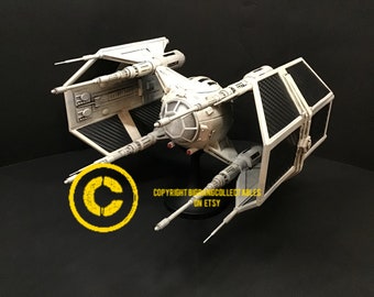 May include: A white TIE fighter model with black wings and a carbon fiber pattern. The model is on a black stand with the text "COPYRIGHT BIGBANGCOLLECTABLES ON ETSY".