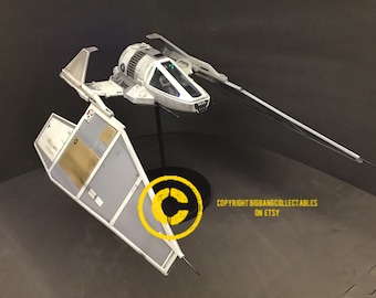 May include: A white model of a Star Wars X-wing fighter with black wings and a gray cockpit. The model is on a black stand with a copyright symbol and the text "COPYRIGHT BIGBANGCOLLECTABLES ON ETSY".