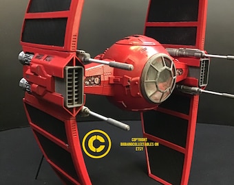 May include: A red TIE Interceptor starfighter model with black details and a carbon fiber pattern on the wings. The model is on a stand and has a copyright notice for BigBangCollectables on Etsy.