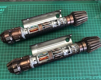 May include: Two disassembled lightsaber props with a copper and silver finish. The lightsabers are open, revealing the internal wiring and components.