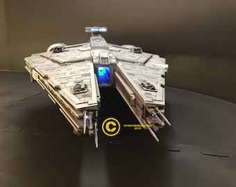 May include: A detailed model of a white spaceship with blue lights, featuring a cockpit window and multiple cannons. The model is on a black surface.