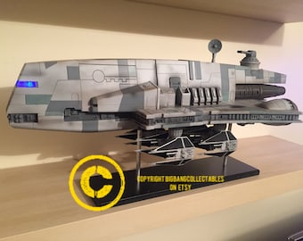 May include: A detailed model of a Star Wars Republic Gunship, painted in a camouflage pattern of gray, white, and green. The model is displayed on a black base with a copyright notice for BigBangCollectables on Etsy.