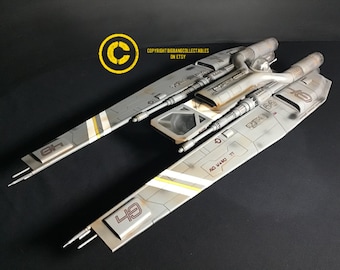 May include: A detailed model spacecraft, predominantly grey with white and yellow stripes. The model features a cockpit and engine details, with the number "49" visible on the wing. The text "NO. WAND. TT" is also visible.
