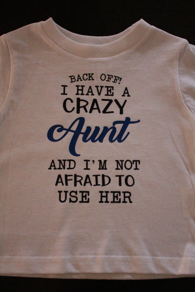 May include: White t-shirt with black text that reads "Back off! I have a crazy Aunt and I'm not afraid to use her."