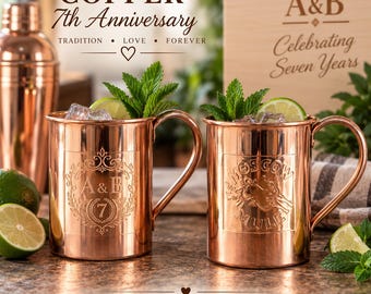 May include: Two copper mugs with handles, each filled with ice, lime slices, and mint sprigs. One mug features an engraved A&B 7 design, the other says MOSCOW MULE. Text includes COPPER 7th Anniversary, TRADITION LOVE FOREVER, A&B Celebrating Seven Years, and A TIMELESS GIFT FOR A REMARKABLE JOURNEY.