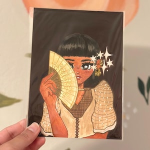 May include: A digital illustration of a person with dark hair holding a yellow fan in front of their face. The person is wearing a light brown dress with a white pattern. The background is dark brown.