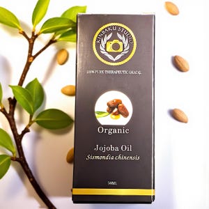 May include: A rectangular box of Kinbaku Studio Organic Jojoba Oil, Sismondia chinensis, 50ml. The box is dark gray with gold accents and a circular logo. The image includes almonds and green leaves.