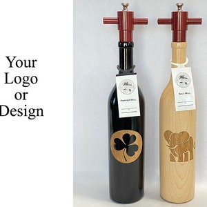 May include: Two wooden salt and pepper mills with red tops. The pepper mill has a shamrock design and the salt mill has an elephant design. The mills are labeled "Pepper Mill" and "Salt Mill".