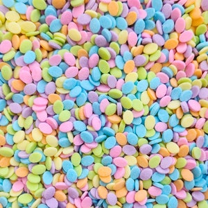 Peut inclure: Des vermicelles de couleur pastel en forme de petits disques ovales. Les vermicelles sont un mélange de bleu clair, de vert clair, de rose clair, de jaune clair et de violet clair.