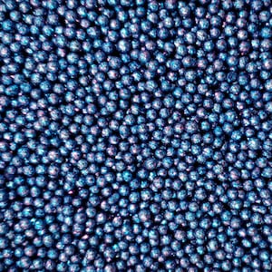 May include: A close-up image of a large quantity of small, round, blue and purple iridescent beads. The beads are arranged in a random pattern, creating a textured and sparkly surface.