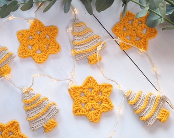 May include: A decorative garland featuring alternating crocheted yellow stars and beige Christmas trees with yellow stripes, strung together with a thin wire of small, glowing star-shaped lights that illuminate the crocheted ornaments.