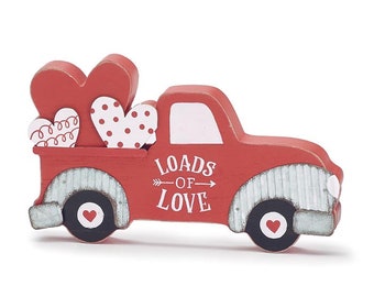 May include: A red wooden truck with a white cab and a bed full of red and white hearts. The truck has a sign on the side that says "Loads of Love".