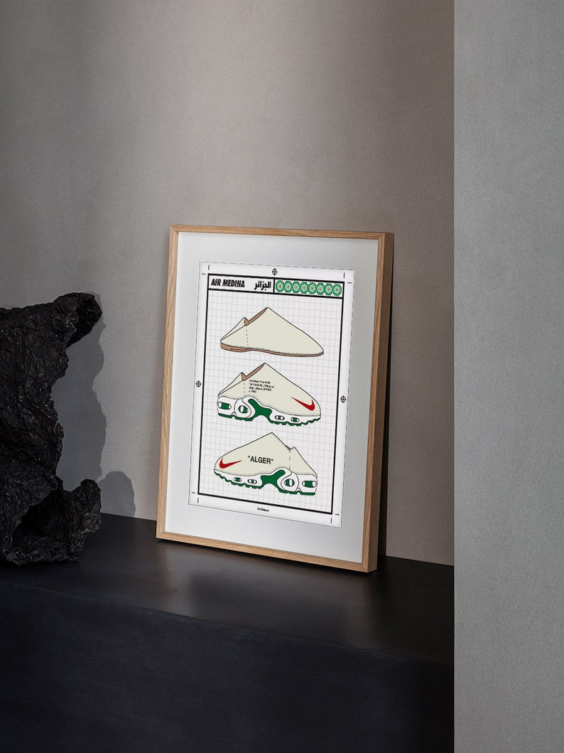 May include: Framed print featuring three illustrations of a white and red sneaker design. The print includes the text "AIR MEDINA" and "ALGER" along with Arabic script. The sneakers have green and red accents and are set against a grid background.