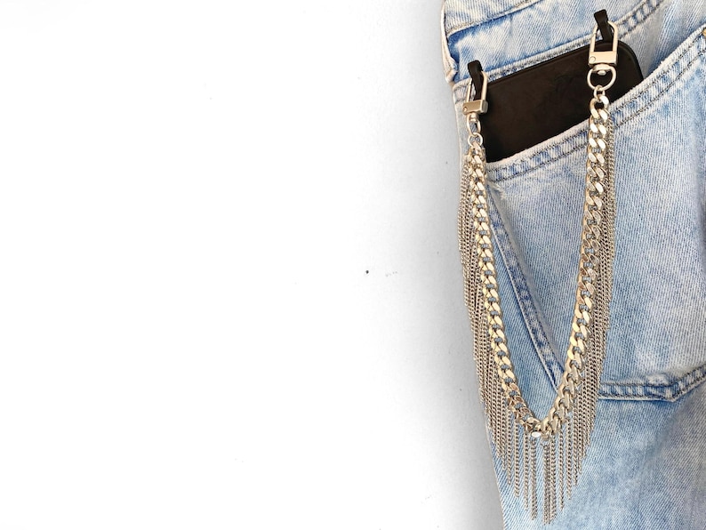 Silver phone strap dropping from a phone case showing its design and movement of fringes