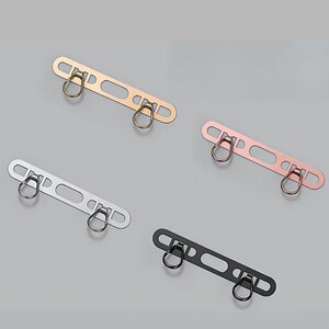 Flat lay of phone hanger accessory available in silver, gold, rose-gold, and black.