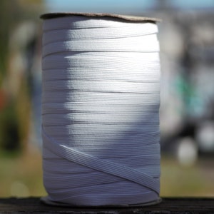 May include: A spool of white elastic cord, wound tightly and ready for use in crafting or sewing projects.