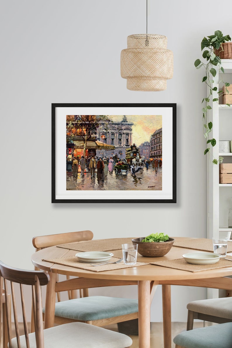 May include: A framed painting depicting a Parisian street scene with people walking and a horse-drawn carriage. The painting is set against a backdrop of buildings with a golden sunset in the background.