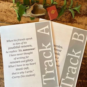 May include: Two pages of a book with the text "Track A" and "Track B" printed in gray on a white background. The text on the left page reads: "When his friends speak to him of his youthful renown, he replies: "Ah, nonsense! I have never thought of writing for renown and glory. What I have in my heart must out; that is why I write." -Czerny (his student)"