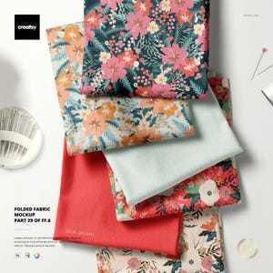 May include: A stack of folded fabric samples with floral patterns in various colors, including pink, orange, and white. The fabrics are arranged in a layered display, with the text "FOLDED FABRIC MOCKUP" visible.