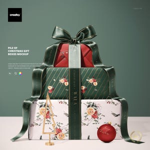 Könnte beinhalten: Ein Stapel Weihnachtsgeschenkboxen, verpackt in gemustertem Papier und mit einem dunkelgrünen Band gebunden. Die oberste Box ist rot, die mittlere Box ist grün mit floralen Akzenten und die untere Box ist weiß mit floralen Akzenten.