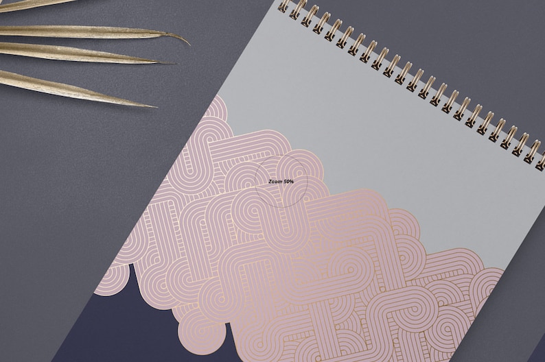 May include: A spiral bound notebook with a gray cover and a pink and gold geometric pattern. The pattern is made up of overlapping circles and lines.
