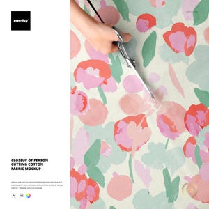 May include: A close-up of a person cutting a floral cotton fabric with scissors. The fabric features a watercolor design of pink and red flowers with green leaves on a cream background. The text "CLOSEUP OF PERSON CUTTING COTTON FABRIC MOCKUP" is visible.