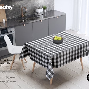 May include: A black and white checkered tablecloth on a wooden table in a kitchen setting. The tablecloth is draped over the table and has a slight overhang on all sides. There are two white chairs on either side of the table. A bowl of green apples sits in the center of the table.
