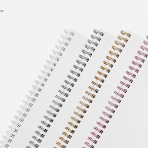 May include: Four spiral bound notebooks with different colored binding coils. The coils are silver, gold, pink, and black.