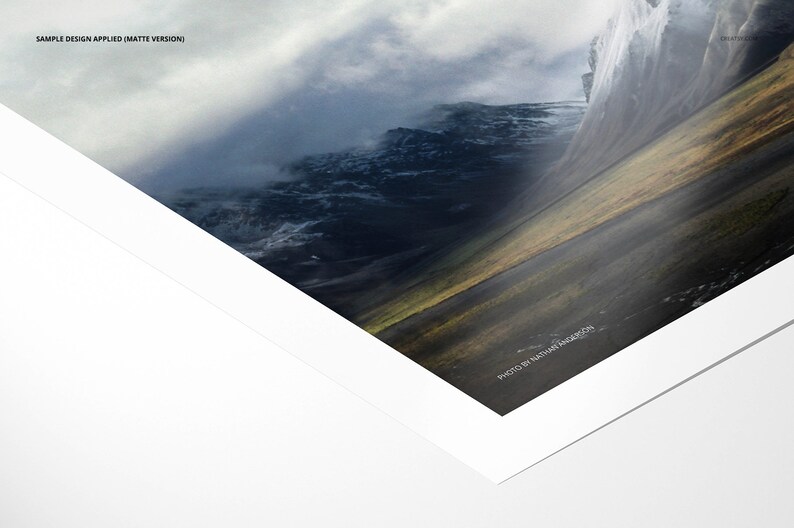 May include: A close-up of a matte photo print of a mountain range with a cloudy sky. The photo is framed with a white mat and a white border. The text "PHOTO BY NATASHA INGARDSON" is printed in the bottom right corner.